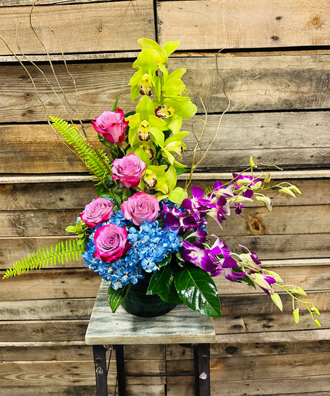 blue and lavender floral arrangement with tall orchid accent