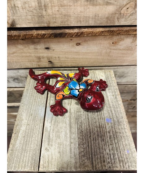 red Talavera tadpole with colorful flower design on back, resting on wooden crate